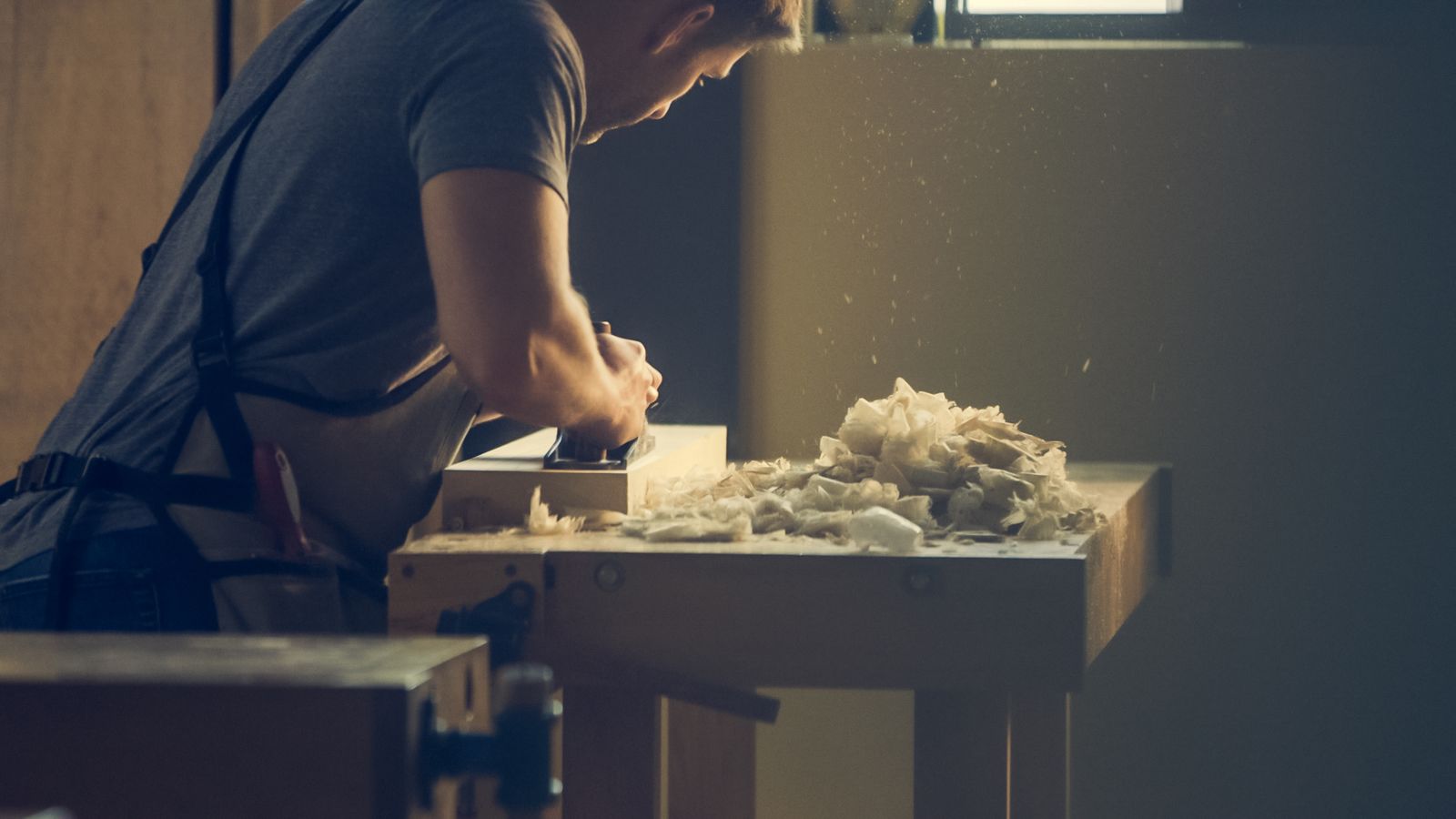 Craftsman hand-shaping a timber component at the Dorose workbench